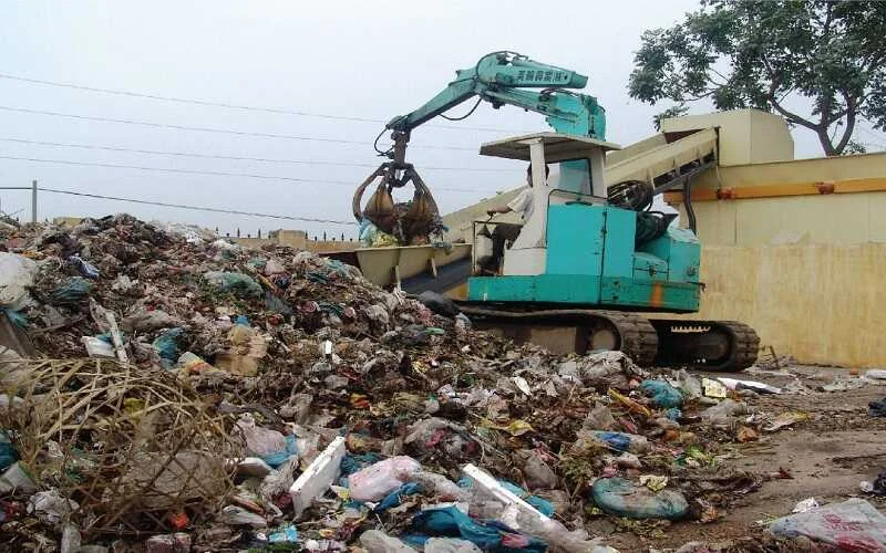 Xe cuốc gom rác thải công nghiệp tại bãi tập kết